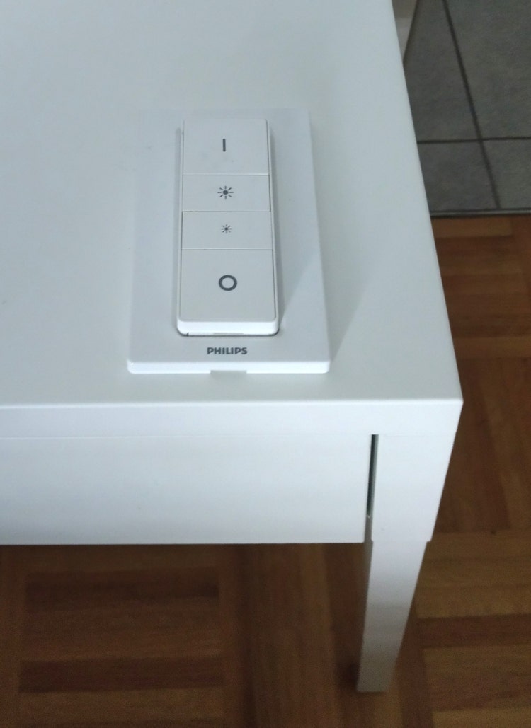 A picture of a bedside table with a portable light switch for the room.